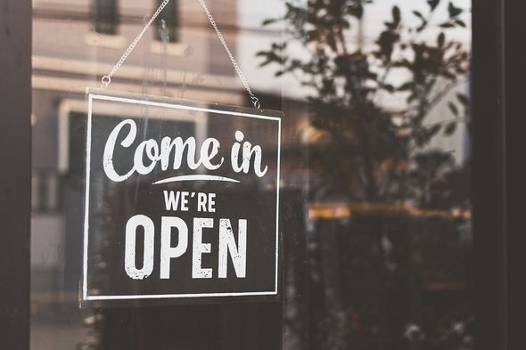 Schild mit der Aufschrift 'Come in WE'RE OPEN' an einer Glastür hängend