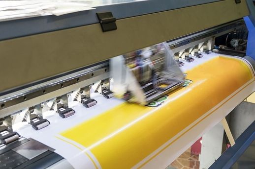 Großformatdrucker druckt gelbes Banner mit Text und Bildern