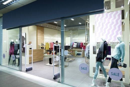 Bekleidungsgeschäft mit Schaufensterpuppen und 'SALE'-Aufklebern an der Glasfront